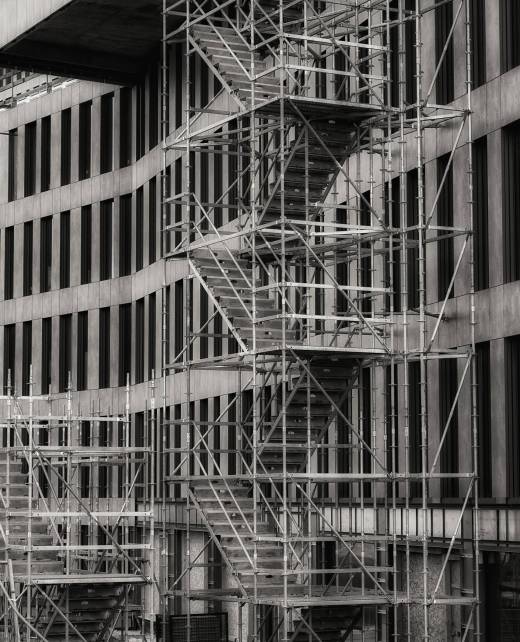A vertical grayscale shot of a staircase outside a building used for the reconstruction
